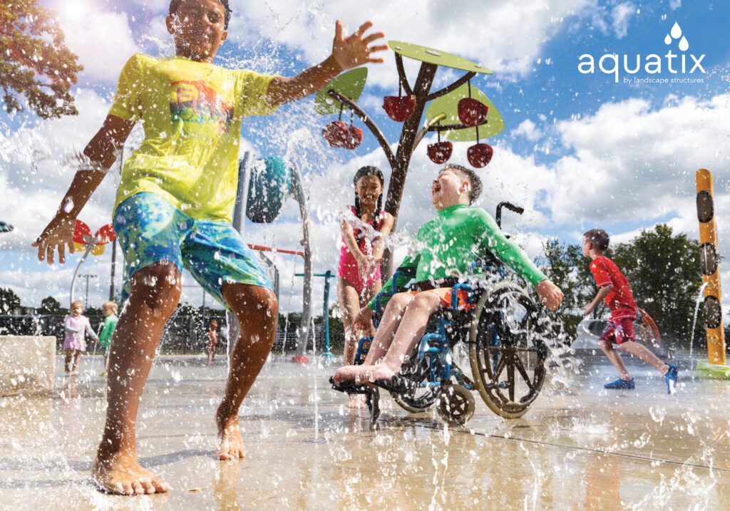 Kids, one using a wheelchair, laugh and play together at a sunny splash park.